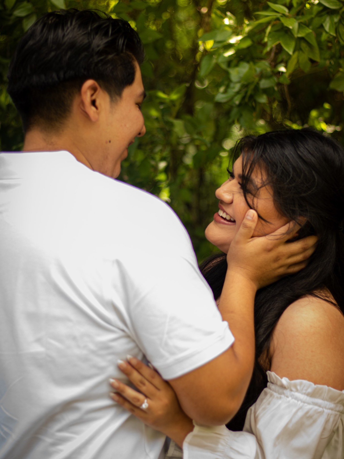 Engaged couple laughing together in soft green light